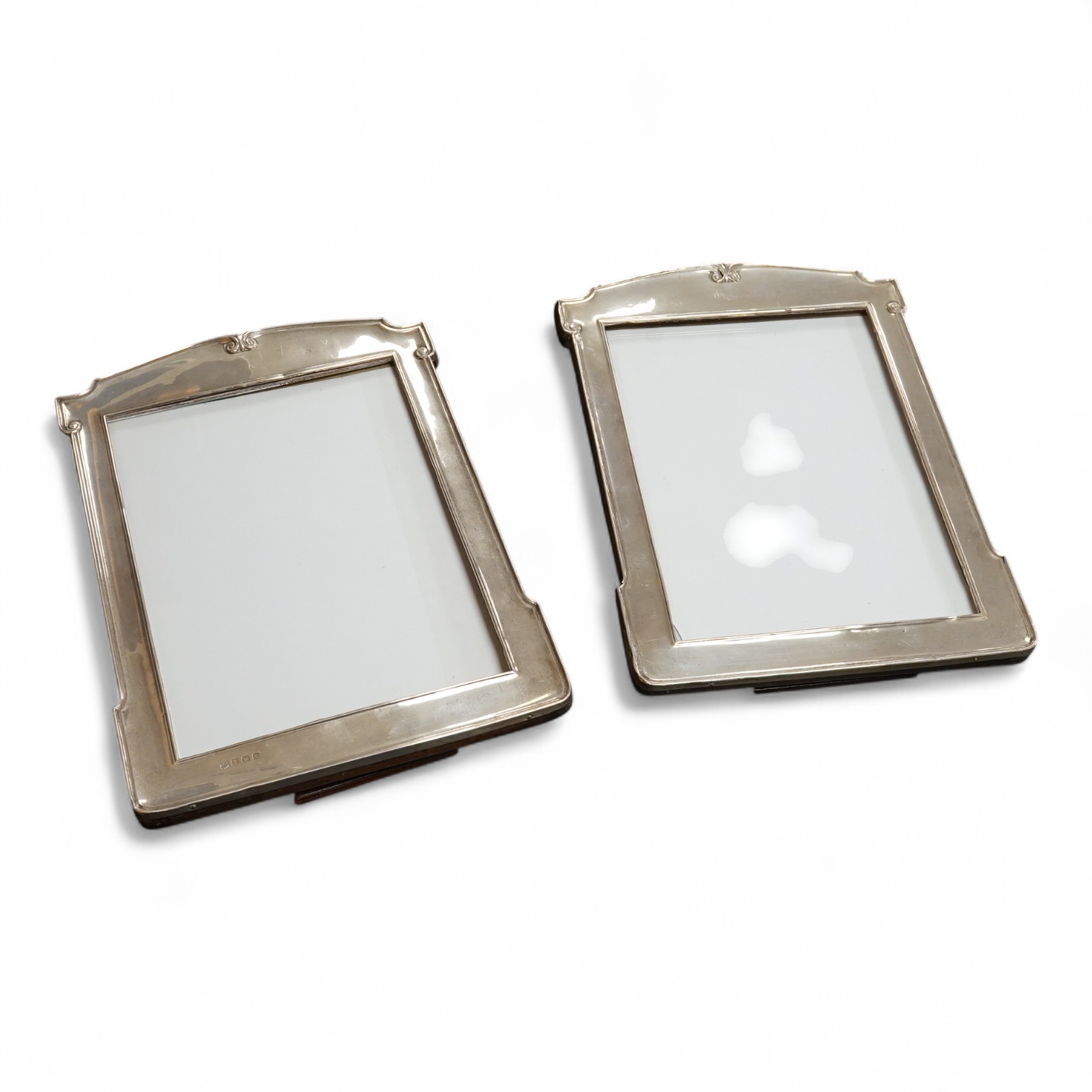 A pair of George V silver mounted shaped rectangular photograph frames, William Neale & Son Ltd, Birmingham, 1922 & 1925, 26.7cm.